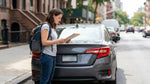 Modern car rental driving down a busy New York street surrounded by tall skyscrapers