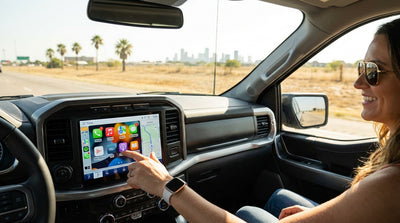 A driver using Apple CarPlay on the dashboard screen of a modern car rental on a highway in Texas