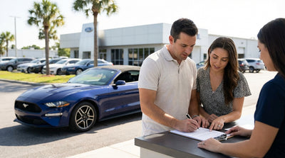 A customer reviews a car rental agreement at a counter in a sunny Florida airport lobby