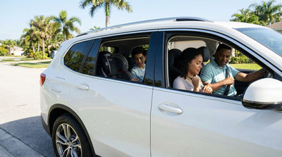 A convertible car hire driving on a sunny, palm-lined coastal road in Florida
