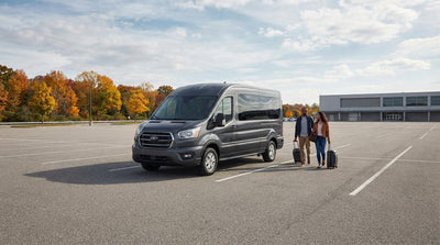 A 12-passenger car rental van driving on a scenic road through the rolling hills of Pennsylvania