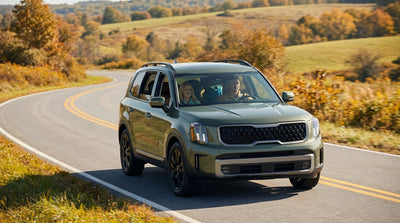 A car hire vehicle driving down a scenic road through a colorful autumn forest in Pennsylvania