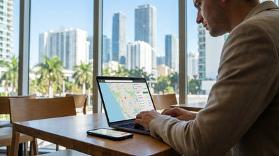 A white convertible car rental driving over a bridge with the sunny downtown Miami skyline in the background