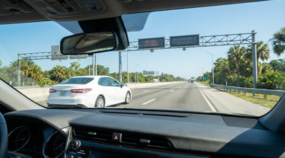 A white car rental driving on a sunny highway lined with palm trees in Orlando, Florida