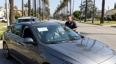 A police car with flashing lights pulls over a car rental on a sunny Los Angeles freeway