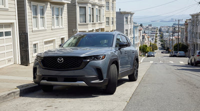 A car rental parked on a steep San Francisco street with its front wheels turned sharply into the curb