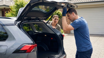 A frustrated driver inspects the open trunk of their car rental on a sunny street in Orlando