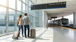 Passengers with luggage walking toward the car rental center at San Francisco airport