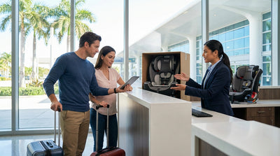 A smiling parent fastens a child into a car seat in the back of a car hire vehicle on a sunny Miami street