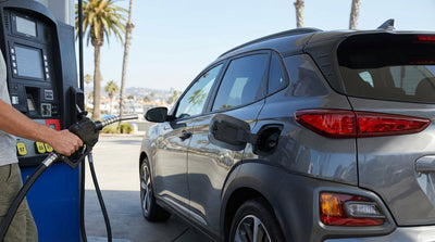 A white convertible car rental parked beside the ocean on a scenic coastal highway in California