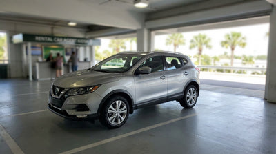 A convertible car hire driving along a sunny, palm-lined coastal road in Florida