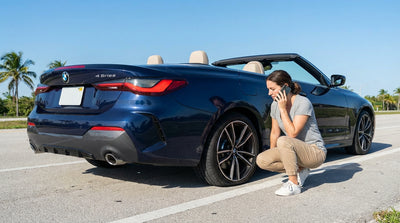 A modern car rental pulled over on a sunny, palm-lined street in Miami