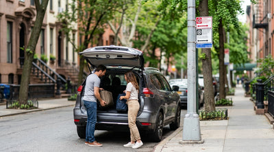 A car rental stopped on a New York City street with someone loading luggage into the trunk