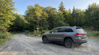 A silver car rental parked on a dirt road at a trailhead in the Adirondack Mountains during the fall