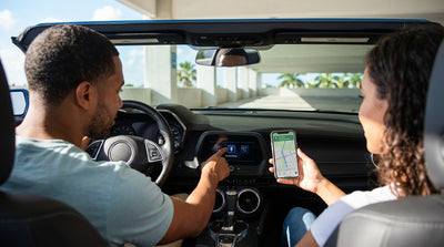 A person in the driver's seat of a car rental in Miami, connecting their smartphone to the dashboard infotainment screen