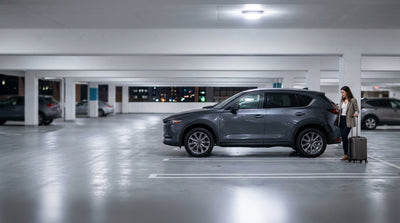A white car rental parked on an upper level of a garage overlooking the bright lights of the Las Vegas Strip at night