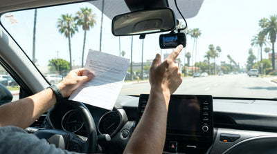 Dashboard view from inside a car hire in Los Angeles, looking out at a sunny street lined with palm trees