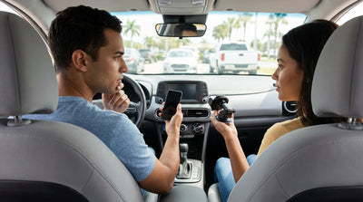 A smartphone mounted on the dashboard of a car rental for navigation on a sunny highway in Florida