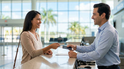 Close-up of a person handing a driver's license to an agent at a Florida car rental desk