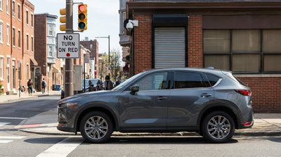 A car hire stopped at a red light next to a 'No Turn on Red' sign on a busy street in Philadelphia, Pennsylvania