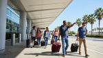 Travelers with luggage board a shuttle for car hire outside a busy LAX terminal in Los Angeles