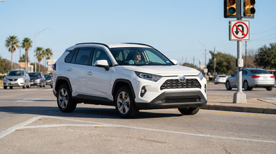 A car rental waits at a red traffic light at an intersection in Texas, with a No U-turn sign clearly visible