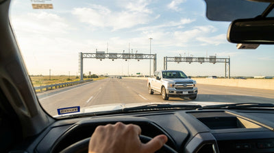 A modern car rental driving on a multi-lane toll highway in Texas under a clear blue sky