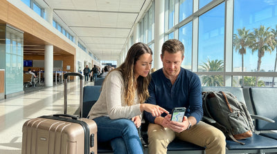 A person plans a route on a phone in their car rental on a sunny street in Los Angeles