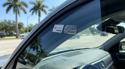 A modern car hire driving under an electronic toll gantry on a sunny Florida highway