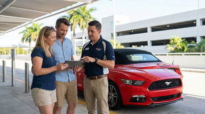 A bright red convertible car rental driving down a sunny street lined with palm trees in Miami