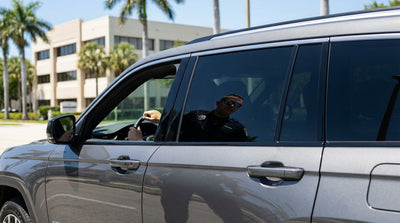 A modern car hire with tinted windows parked on a sunny Florida road next to palm trees