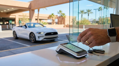 A person handing a credit card to an agent at a car hire counter in the Las Vegas airport terminal