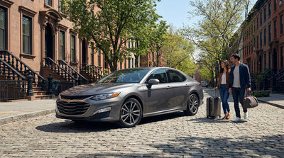 A sleek car hire vehicle driving through the busy, skyscraper-lined streets of New York City on a sunny afternoon
