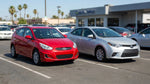 A silver economy and a red compact car rental parked side by side on a sunny road in the United Estates