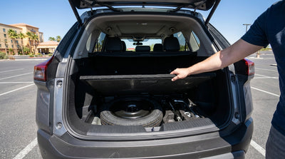 A person inspects the jack and tools in the open trunk of a car rental on a sunny day in Las Vegas