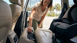 Parent securing a child safety seat in the back of a Florida car rental on a sunny day