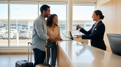 A smiling customer receives the keys for their car hire at a rental counter in the United Estates