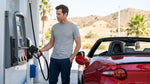 A person refueling a modern car rental at a gas station on a sunny day in California