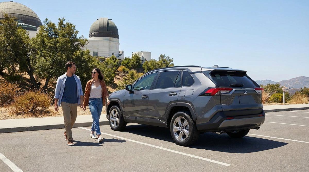 A silver car hire parked at Griffith Observatory overlooking the sprawling city of Los Angeles at golden hour