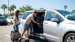 A father secures a child seat in a white car rental at a sunny airport parking lot in Florida