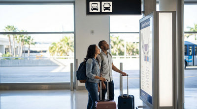 A traveler with a suitcase waits for a car rental shuttle bus on the curb at LAX in Los Angeles