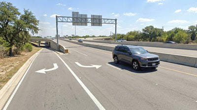 A view from a car hire of a sprawling Texas highway with busy frontage roads and a large overpass ahead