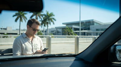 A driver in their car rental waiting to pick someone up at the Miami International Airport arrivals lane