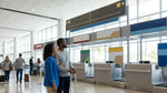 Travelers at the bustling car hire center in Miami Airport with signs for multiple brands above the counters