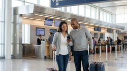 A traveler rolling luggage towards a Hola car hire desk in Los Angeles