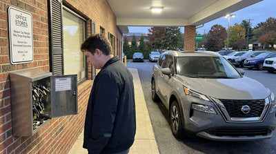 A person holds car keys in front of a full after-hours key drop box for a car hire in Pennsylvania