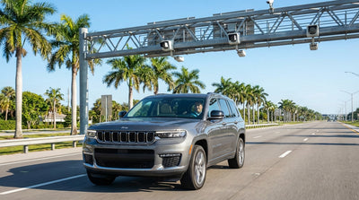 A car hire driving under an electronic toll gantry on a sunny highway in Miami
