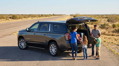 A black Chevy Suburban car rental driving on a scenic highway through the Texas Hill Country