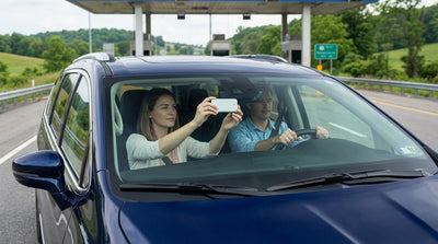 A silver car rental approaches an E-ZPass toll gantry on a highway in Pennsylvania
