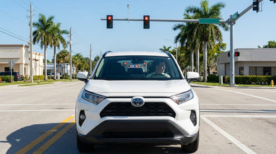 Police car with flashing lights in the rearview mirror of a Florida car hire stopped at a red light intersection